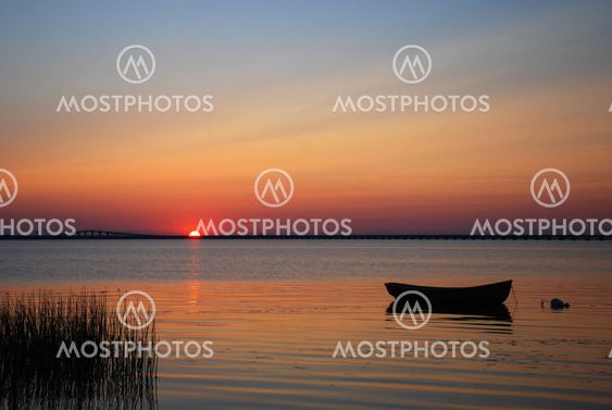 Lone rowboat in calm water at sunset