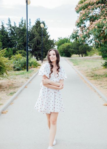 brunette woman in white polka dot summer dress walking...