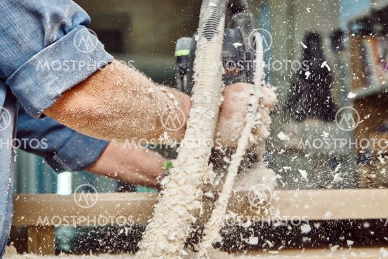 Carpenter with hand electric router machine at work....