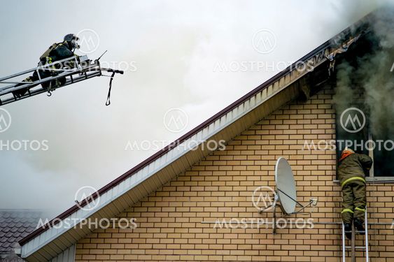 A firefighter puts out a burning building with height...