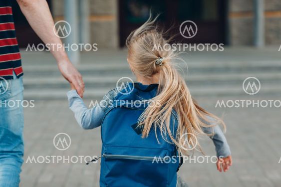Rear view of father walking back to school with his...