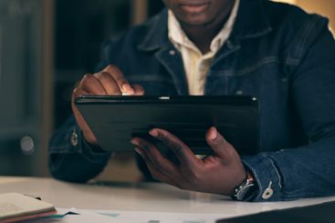 Black man, tablet and working at night in office with...