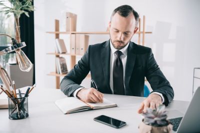 handsome businessman writing in notebook at workplace
