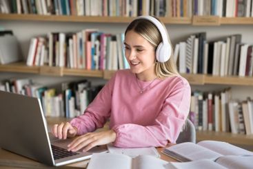 Woman studying online using laptop sit at desk in library