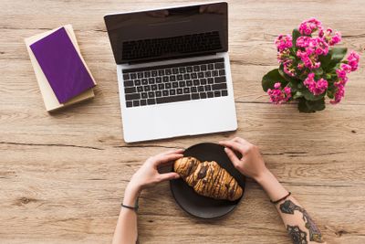 cropped shot of woman at workplace with laptop, books and...