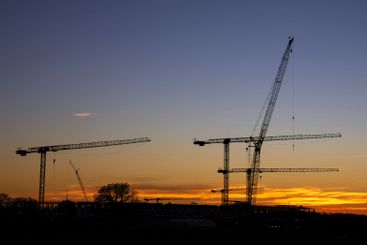 Silhouettes of construction cranes against the evening...