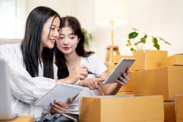 Two positive Asian women are discussing while preparing...