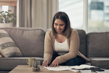 Bills, smile and woman on sofa writing finance notes...