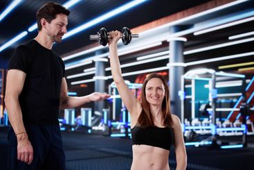 Female Personal Trainer Helps Woman with Shoulder Exercise