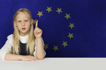 Curious young child girl pointing up on flag of European...