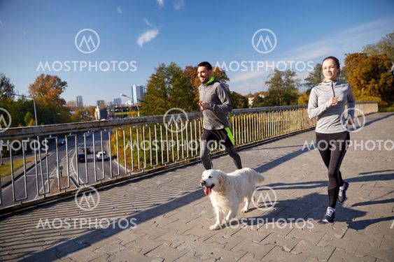 happy couple with dog running outdoors