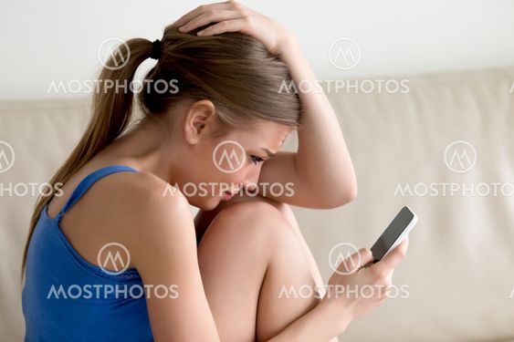Woman crying while reading message on cellphone