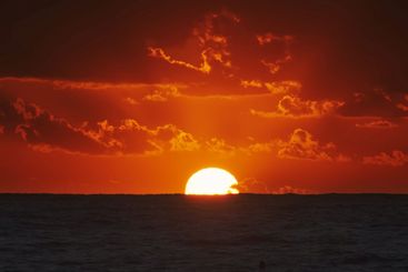 Sunset over ocean with dramatic clouds at dusk