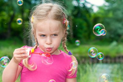 Cute little girl blowing soap bubbles