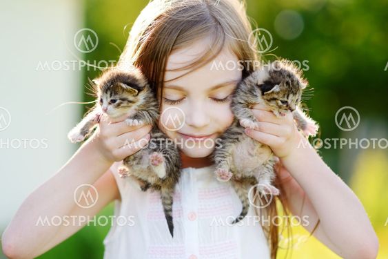 Adorable little girl playing with small kittens