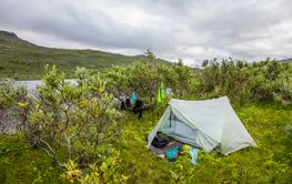 Tent and trees by river and hill