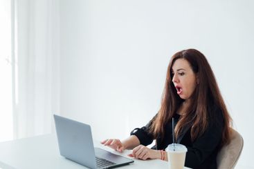 Businesswoman brunette sitting at desk surprised online...