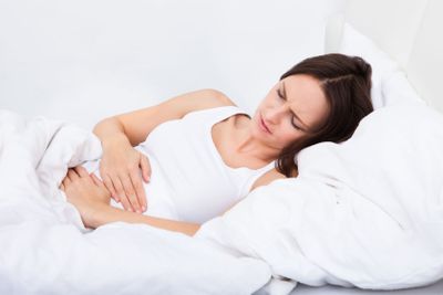 Woman with stomach ache lying on bed