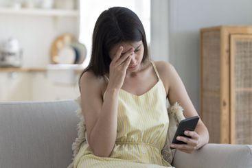 Distressed girl sit on couch read bad news on cellphone
