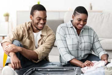 Happy Black Spouses Sitting Near Suitcase Preparing For...