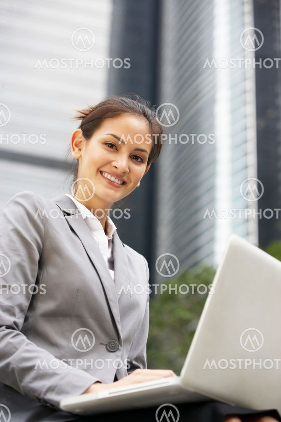Hispanic Businesswoman Working On Laptop Outside Office