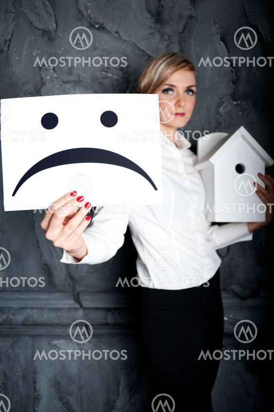 The young business lady in one arms holds the house, and in other sad smile