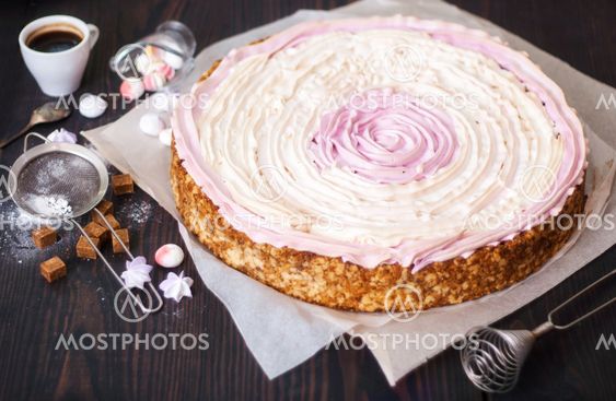 Pink cake with berries and meringue on the kitchen table.