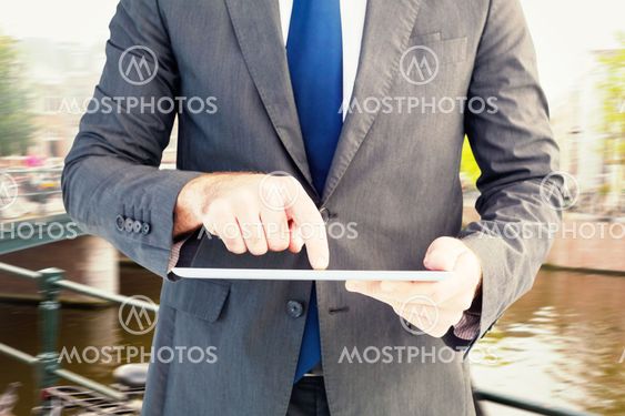 Composite image of businessman using his tablet pc