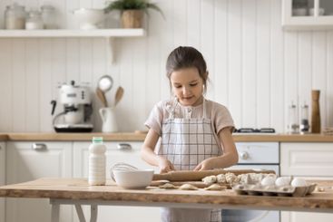 Smart little girl enjoy cooking from dough at home alone