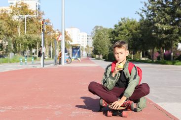 Handsome teenager standing with skateboard. Adolescent...