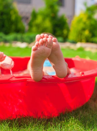 Closeup of little kid's legs in small red pool