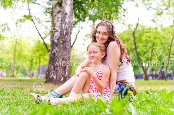 mother and daughter sitting together on the grass