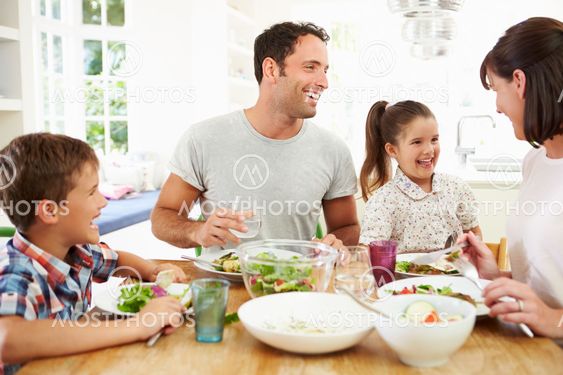 Family Eating Meal Around Kitchen Table Together