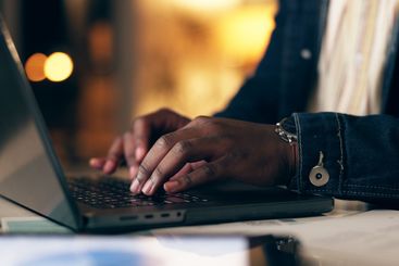 Black man, laptop and working at night in office with...