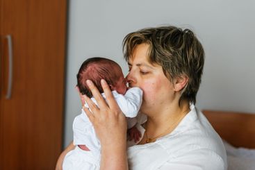 Mother kissing her one month old baby son at home