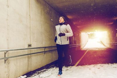 happy man running along subway tunnel in winter