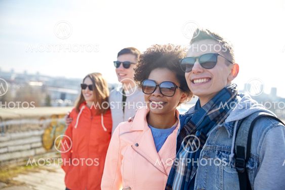 happy teenage friends in shades hugging on street
