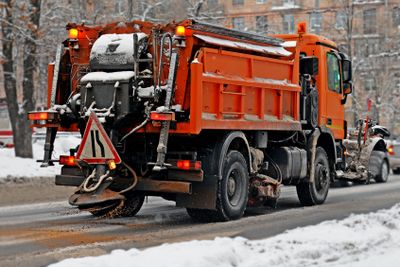 The big red snowplow sands the carriageway 