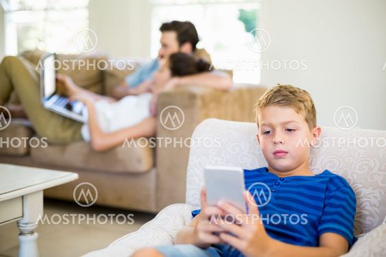 Boy sitting on sofa and using mobile phone