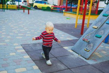 A fair-haired one-year-old boy in jeans and sneakers...