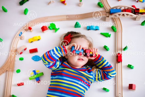 Little girl playing with wooden trains