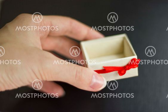 A hand holding a gift box on a black background