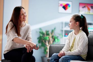 Young female child therapist comforts a depressed kid...