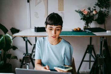 Young female freelancer talking through smart phone while...