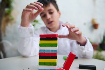 Boy concentrating on stacking colorful blocks at a table