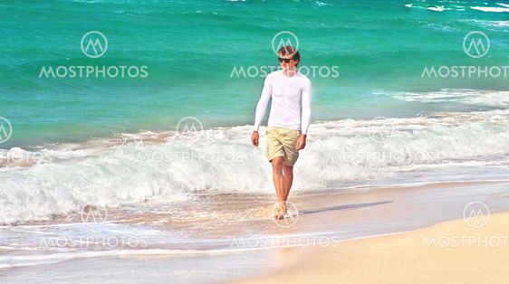 Young Man walking on the Beach Seaside sand with blue Sea on background Summer Travelling Tropical island