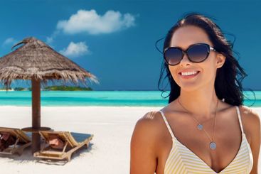 smiling young woman in sunglasses on summer beach