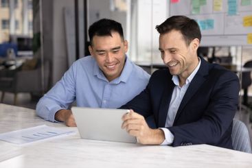 Cheerful multiethnic male colleagues watching online...