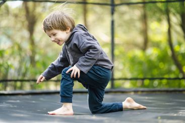 Little boy jumping on a trampoline in a backyard on warm...