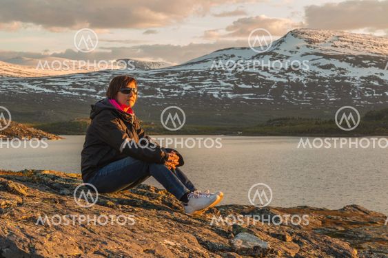 Woman sitting on rock in sunset